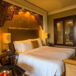 Elegant hotel room in Dubai with ornate decor and plush bedding.