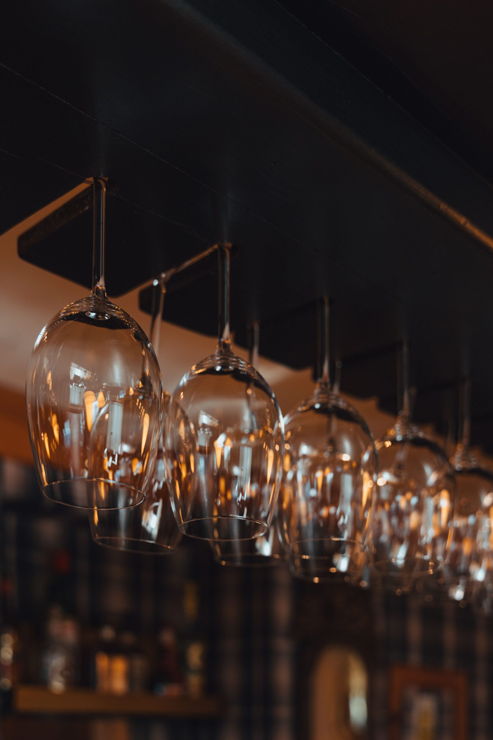 Amenities Row of elegant glass wine globes hanging upside down with warm lighting, creating a cozy bar ambiance.